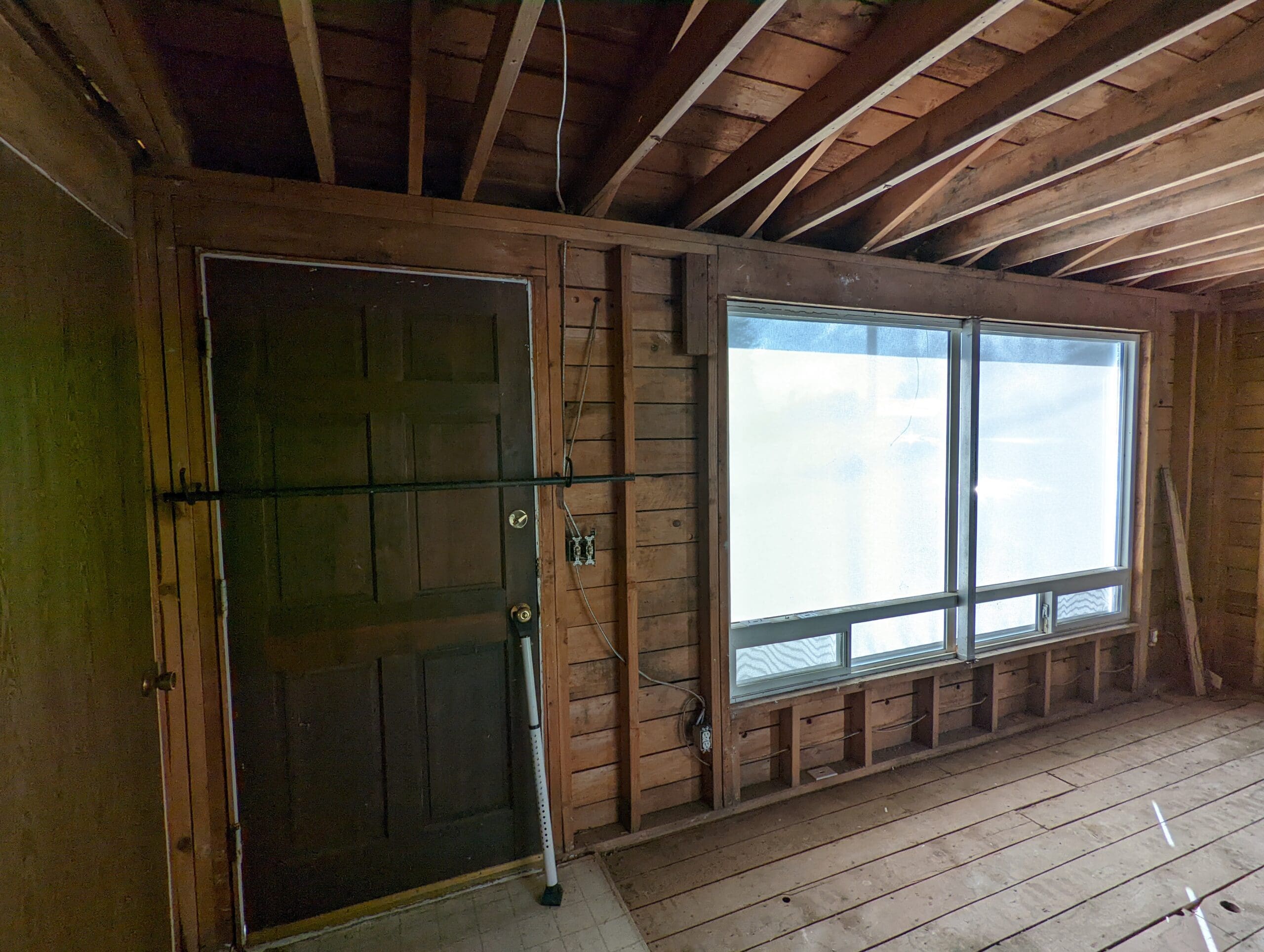 Before smoke-seal: entry door and large front window with open framing