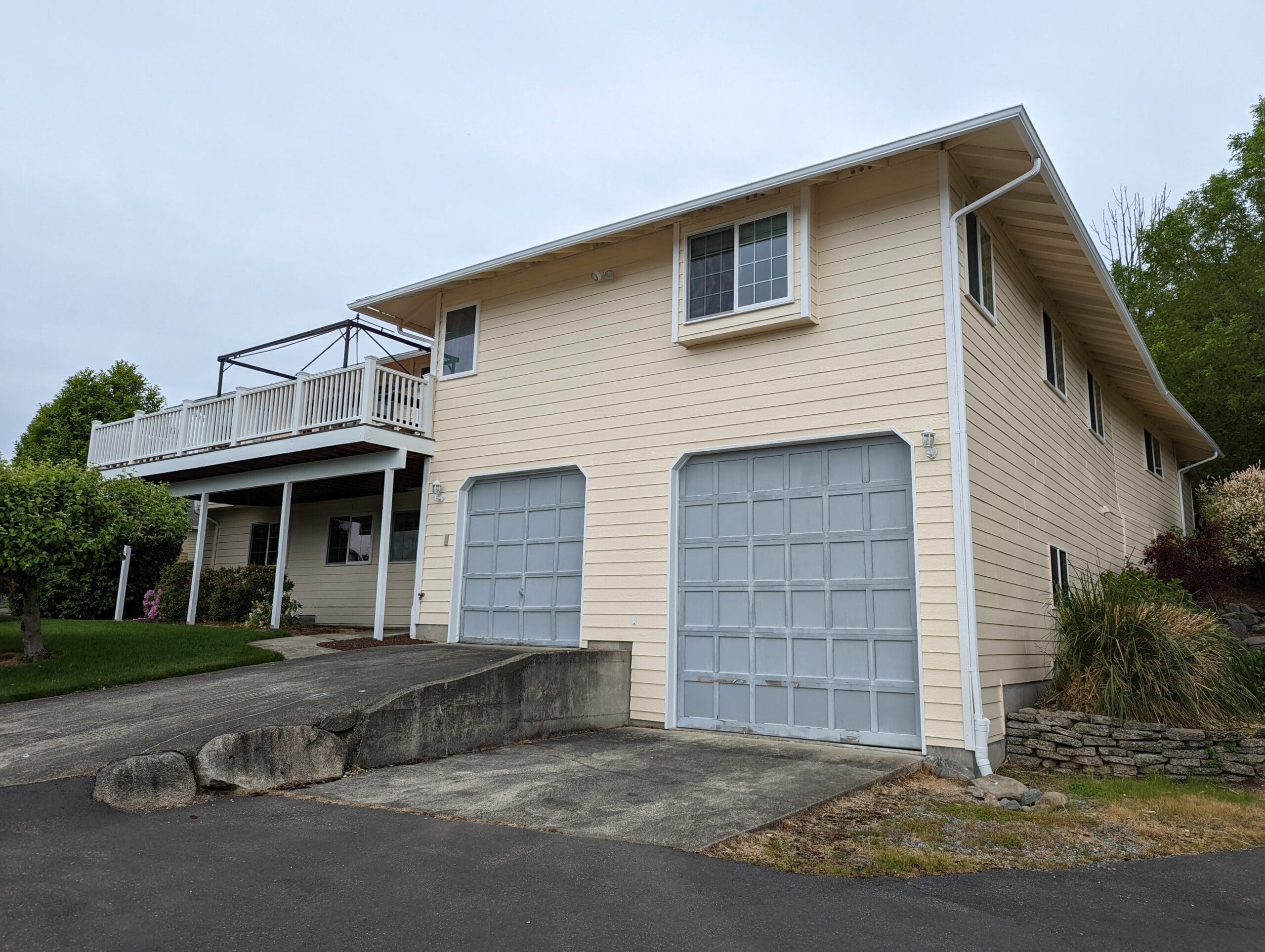 Warm cream exterior house paint on garage doors and upper deck wall after Shanco repaint