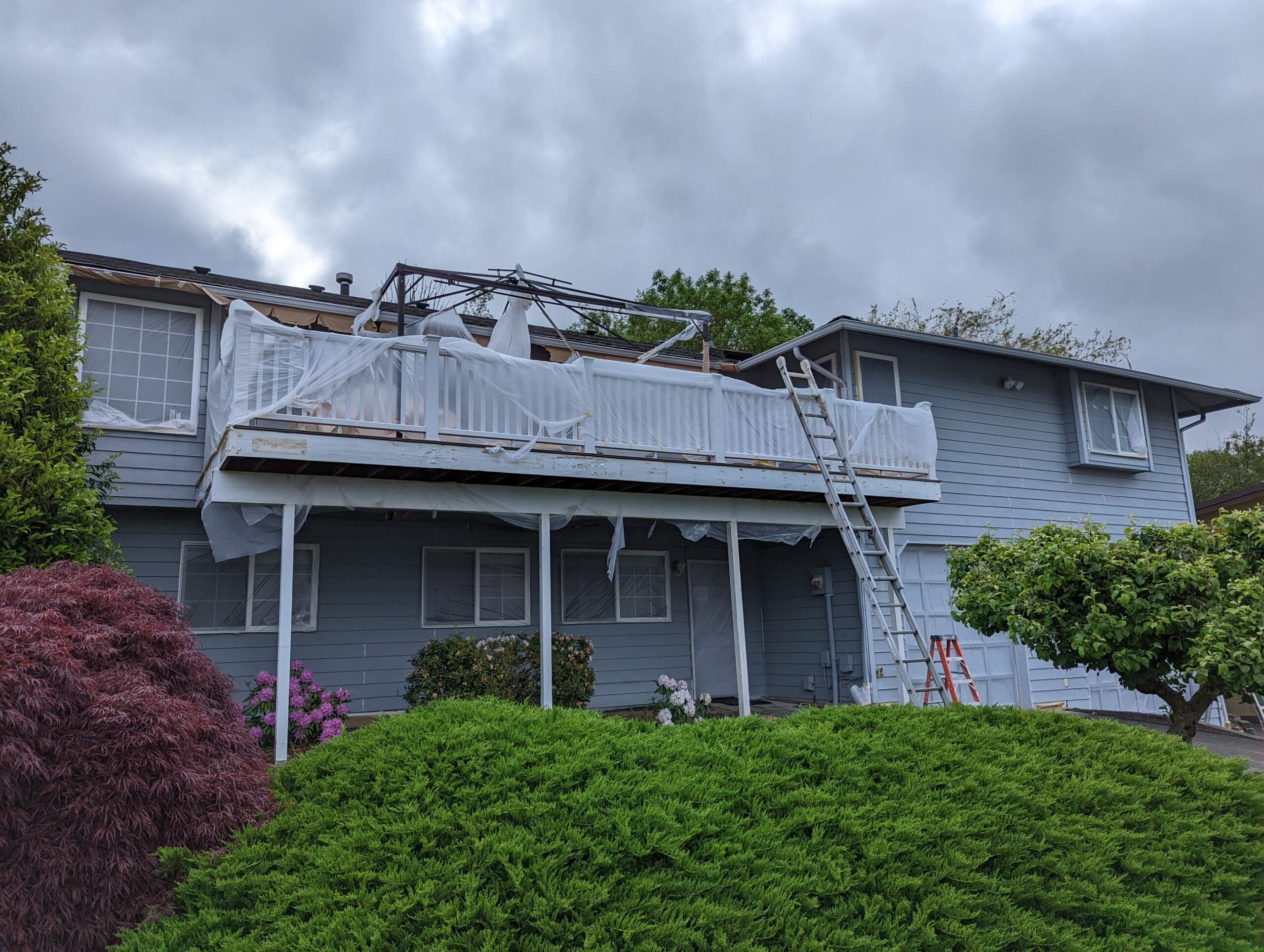 Home masked off with plastic and paper at front deck during exterior paint prep by Shanco
