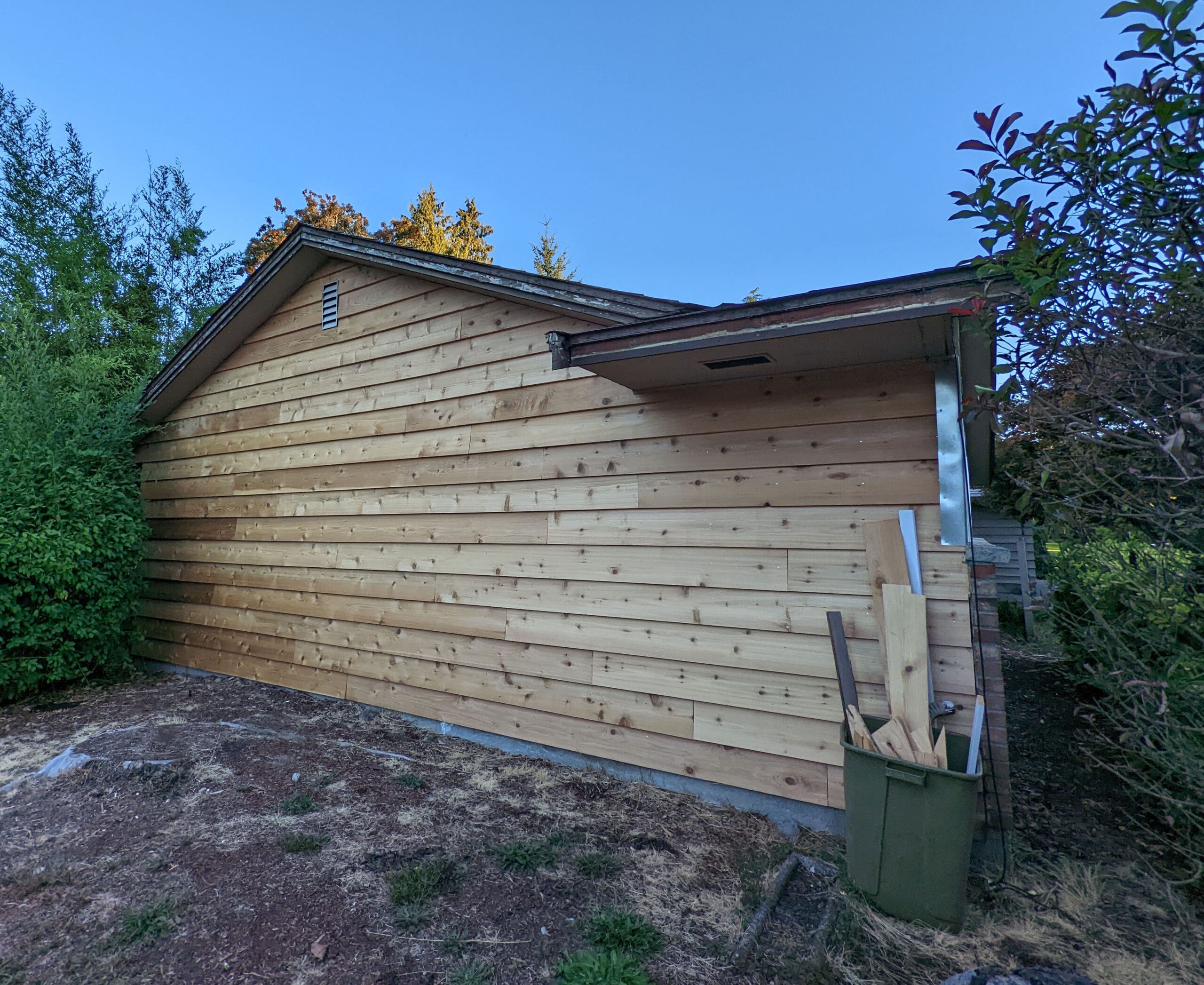 In‑progress photo showing new cedar lap siding installed before painting.